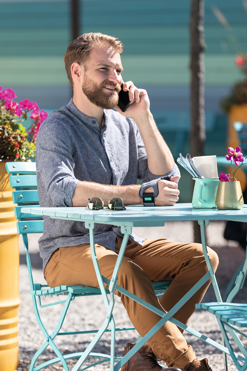 A man wearing a thumb brace is sitting in a café