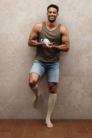 Juzo Intenso Mężczyzna nosi Juzo Intenso w kolorze sezamowym, a w dłoni trzyma króliczka