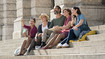 Friends sit on a staircase. Some of them are wearing compression stockings