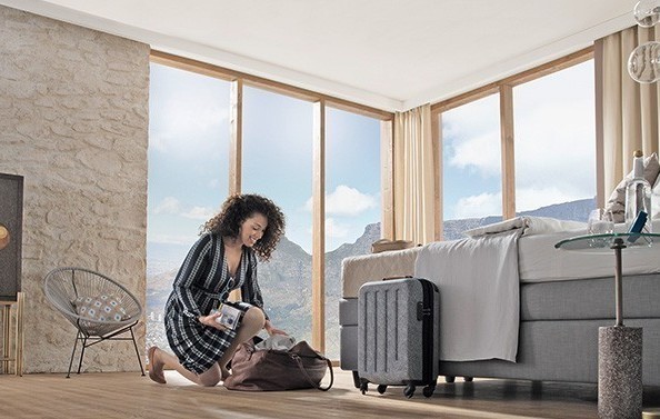 Frau packt aus Frau packt Reisetasche im Hotelzimmer aus