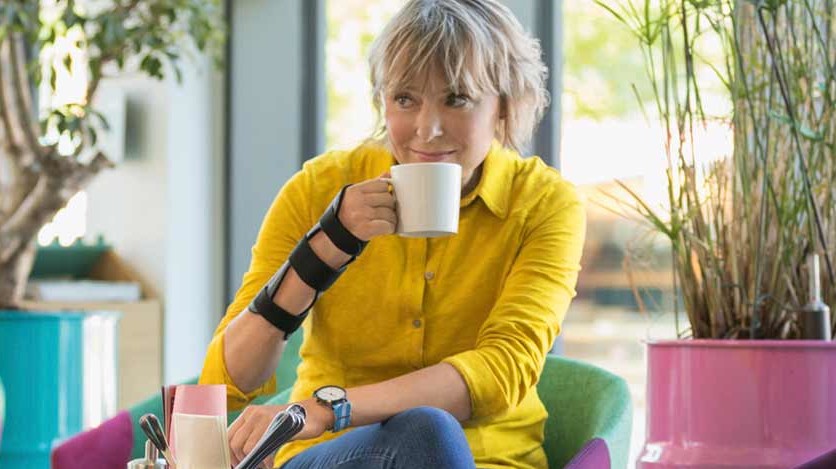 Mainteaser Karpaltunnelsyndrom (content-sider) Kvinde bærer håndledsortosen JuzoPro Manu Xtec og holder en kop i hånden