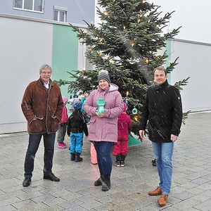 Uwe Schettler und Jürgen Gold (von links) freuen sich mit der stellvertretenden Kindergartenleitung des Julius-Kindergartens Jennifer Schade (Mitte) über den von den Kindergartenkindern geschmückten Weihnachtsbaum.