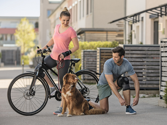 Artrose  Een vrouw en een man laten met een fiets een hond uit