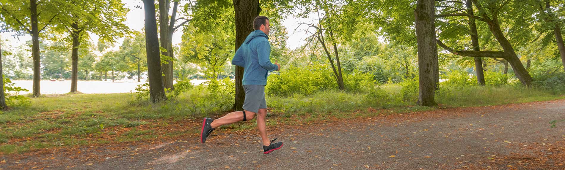 Patellaband Mann joggt im Wald und trägt dabei das Patellaband