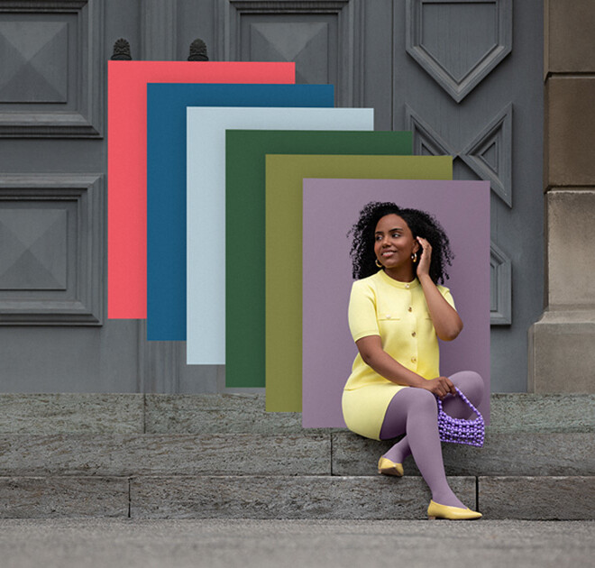 Une femme est assise sur des marches en pierre devant un portail. Elle porte un ensemble deux pièces jaune clair et un bandage compressif violet. Derrière elle, on aperçoit des aplats de couleurs tendance.