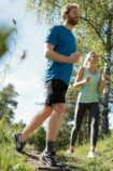 Ein Mann und eine Frau sind beim Joggen im Wald, der Mann trägt die Sprunggelenkbandage JuzoFlex Malleo Xtra Anatomic