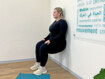 Frau macht an einer Wand die Übung Wandsitz