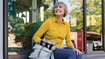 A woman sits on a windowsill. She is wearing a wrist orthosis on her wrist.
