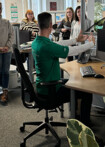 Ein Ergonomie-Berater sitzt an einem Schreibtisch und zeigt die richtige Einstellung des Arbeitsplatzes