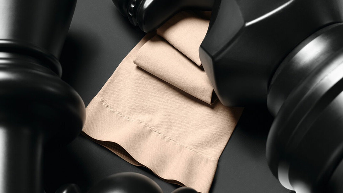 Der Juzo Dynamic Strumpf liegt zwischen zwei großen Schachfiguren