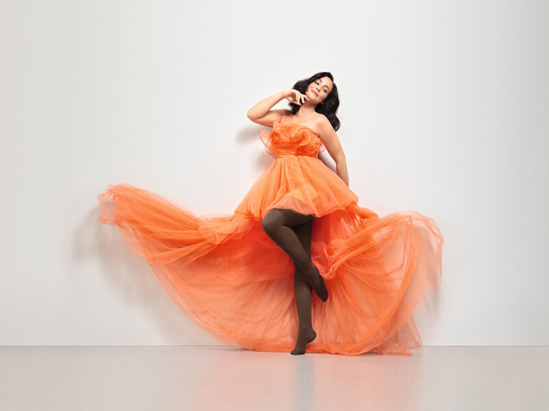 Frau trägt ein orangenes Tüllkleid und den Juzo Inspiration in Kakao