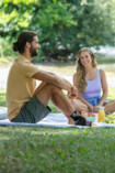 Ein Mann und eine Frau sitzen auf einer Picknick-Decke und sie lächeln sich an, er trägt die Sprunggelenkbandage JuzoFlex Malleo Xtec Strong