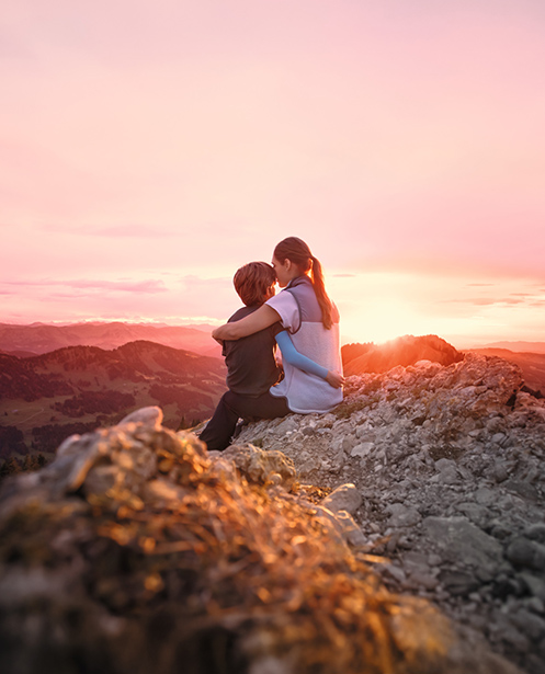 Traitement des cicatrices par compression Une mère est assise avec son enfant au sommet d'une montagne. L'enfant porte une manchette de compression.