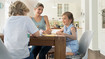 A family sits at the table. The daughter has a scar on her arm.