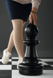 Woman wears Juzo Dynamic, stands on a large chessboard and touches the black bishop